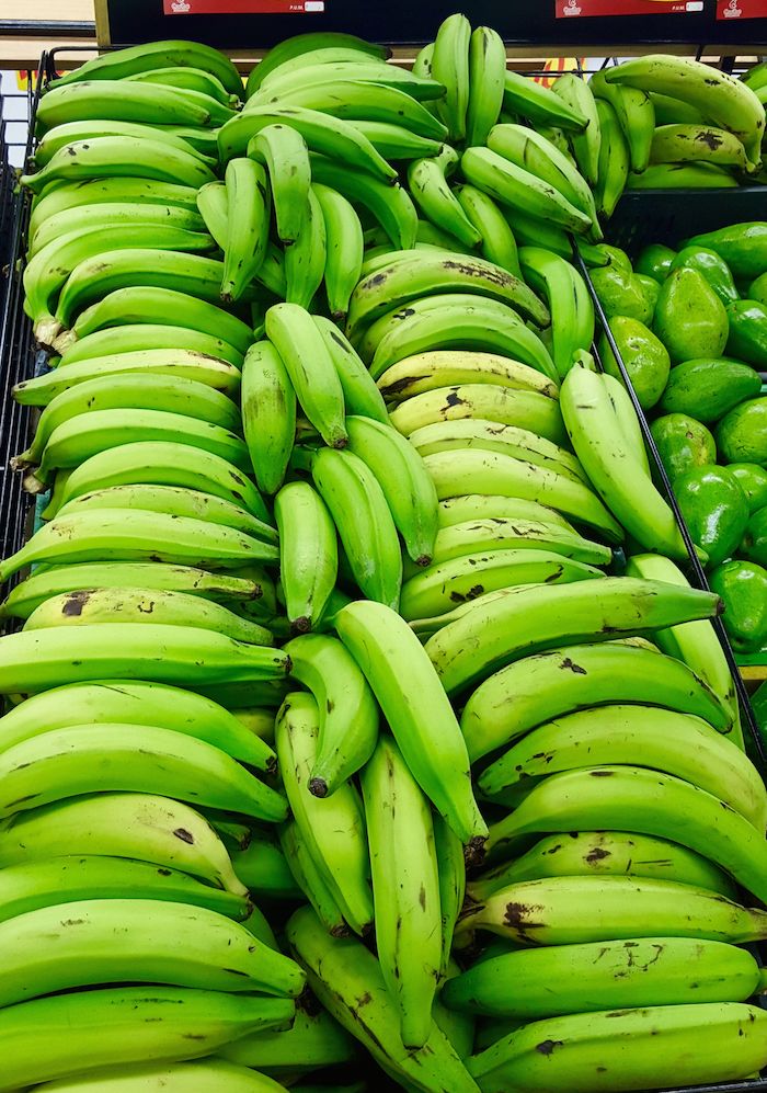 several bunches of green bananas on display in a grocery store