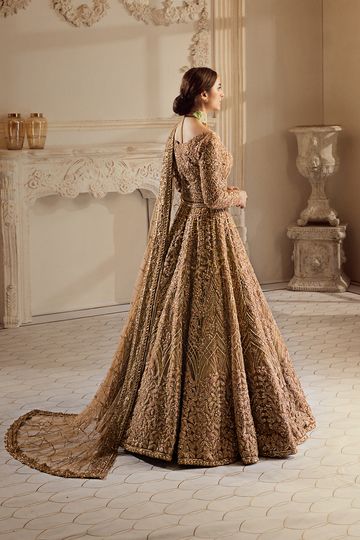 a woman standing in a room wearing a long dress with an intricate pattern on it