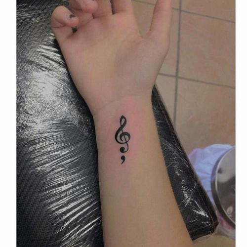 a woman's hand with a small tattoo on her left wrist and a musical note in the middle