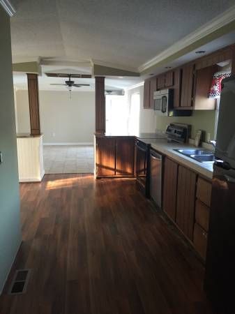 an empty kitchen and living room with wood flooring in the middle of the room