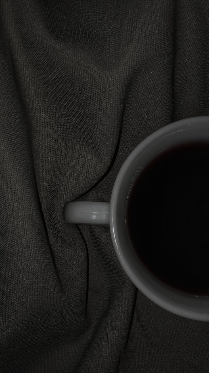 a cup of coffee sitting on top of a black cloth