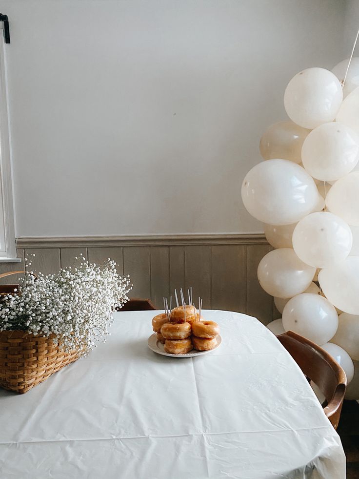 two donuts on a plate sitting on top of a table with balloons in the background