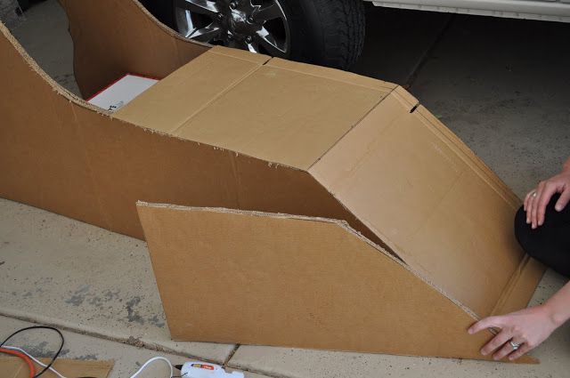 a woman sitting on the ground next to an open cardboard box with wires in it