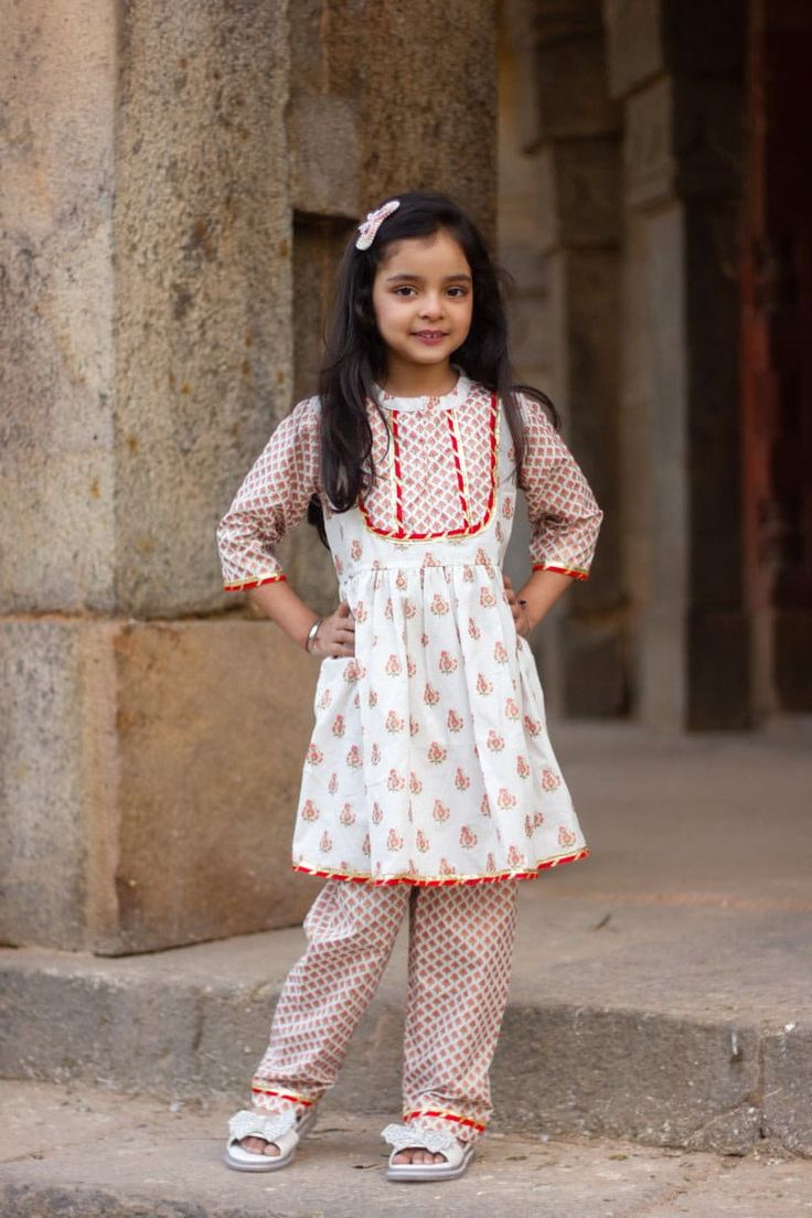 "Perfect for summer weddings and festivals this lehengha and top (set of 2) is an eye turner. Shouting with oodles of comfort during the festivities this cotton peplum suit is going to make your little one feel like herself while enjoying the festive season. Kurta - White base with pink floral print. Stand collar and embellished yoke. Payjama - Printed floral payjama makes it a comfy wear for your little ones as it comes with elasticated waist with drawstring for easy wear. Floral print  Fabric Festive Block Print Pant Set For Eid, Anarkali Block Print Sets For Summer, Anarkali White Pant Set For Festive Occasions, Eid Festive Block Print Pant Set, Festive Cotton Lehenga With Printed Motifs, Bollywood Style Printed Sets For Puja, Festive Anarkali Peplum Set, Fitted Cotton Salwar Kameez For Puja, Festive Cotton Sharara With Printed Motifs