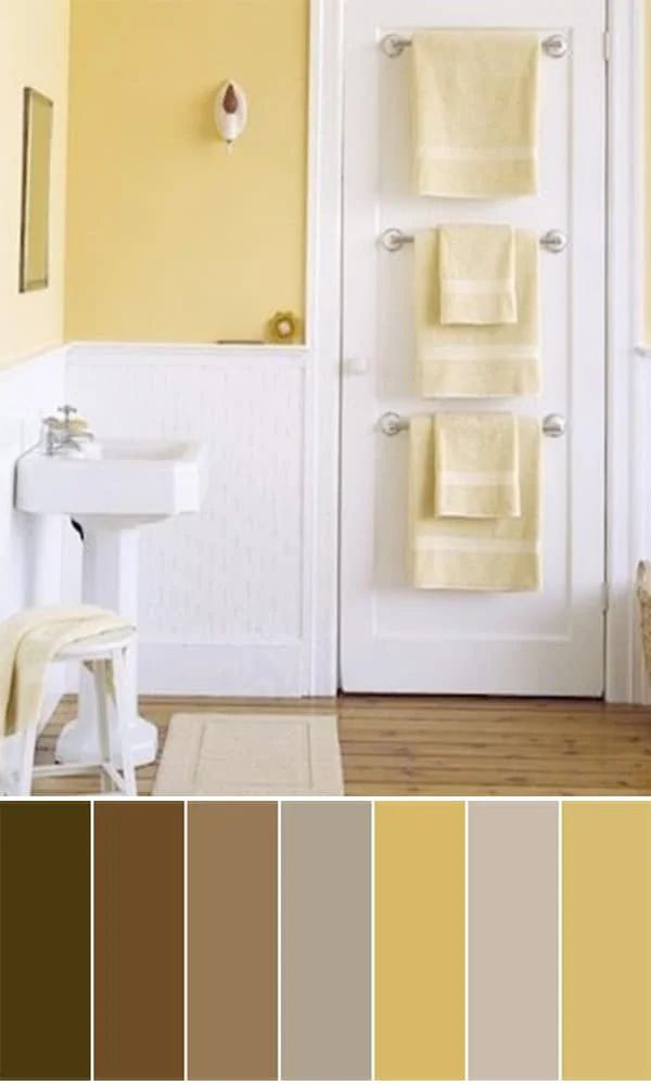 a bathroom with yellow walls and white fixtures, including towels on the rack in front of the door