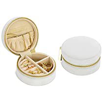 an open jewelry box sitting on top of a white table next to a container with gold trimmings