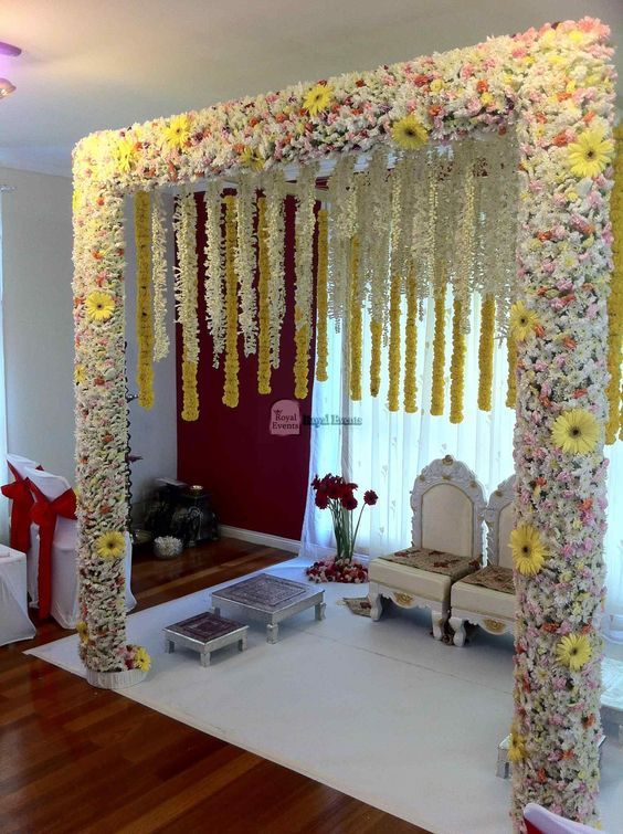 a decorated stage with flowers on the ceiling and white furniture in front of it for a wedding ceremony