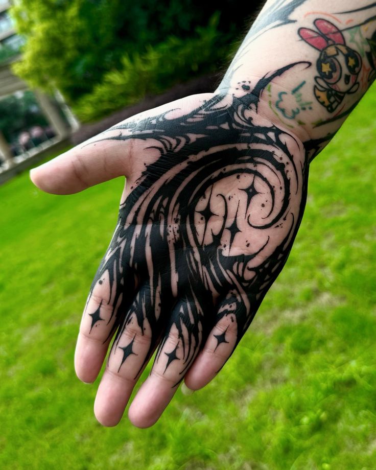 a person's hand with black ink on it in the middle of a grassy area