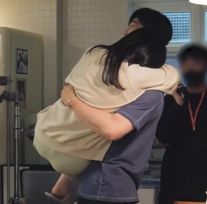 a woman is carrying another woman in her arms as they stand next to a refrigerator