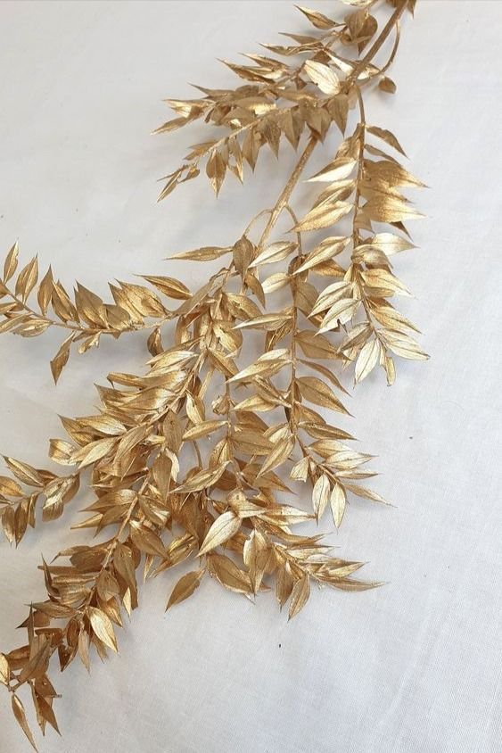 some gold colored leaves on a white surface