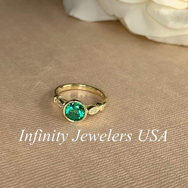 "The ring pictured is lab created emerald with moissanite accents #7056 -Approximate total carat weight: 1.26ctw diamond equivalent -Center Stone Size: 7mm - approx. 1.20ct diamond equivalent -Center Stone Shape: round -Gem Type: lab created emerald -Stone Clarity: VS2 -Stone Color: green -Moh's Scale: 8.5 hardness -Accent Stones: 2 rounds - approx. 0.06ctw. diamond equivalent -Gem Type: moissanite -Stone Clarity: VS2 -Stone Color: FG -Moh's Scale: 9.25 hardness -Metal Type and Purity: 14k white Moissanite Emerald Ring In Yellow Gold For Promise, Fine Jewelry Moissanite Emerald Ring With Accent Stones, Diamond May Birthstone Ring With Center Stone, Diamond Birthstone Ring With Center Stone For May, Heirloom Emerald Ring With Accent Stones And Round Cut, Heirloom Style Emerald Ring With Accent Stones, Heirloom Emerald Ring With Accent Stones, Promise Emerald Ring With Diamond Bezel Setting, 14k Gold Emerald Ring With Center Stone