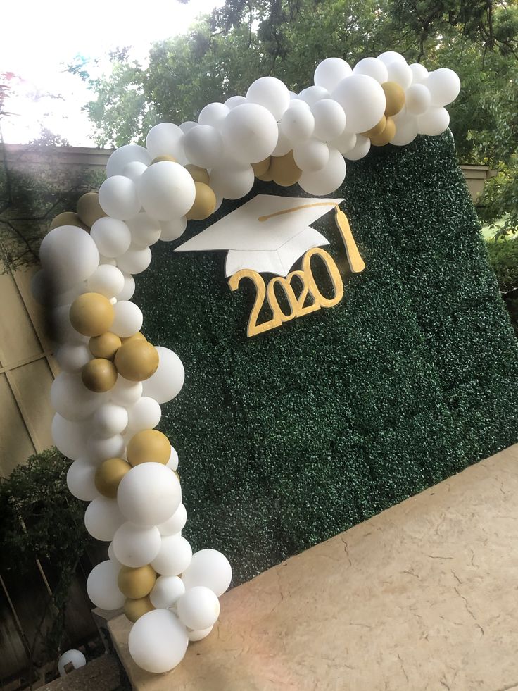 a graduation balloon arch decorated with white and gold balloons