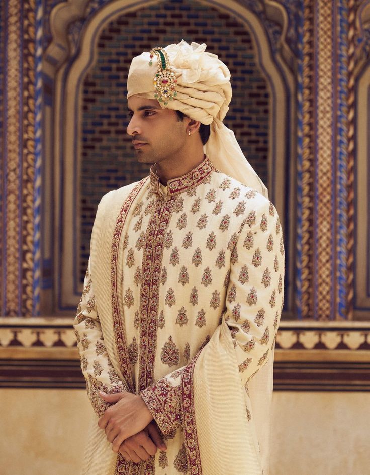 Radiate sophistication in this light beige raw silk sherwani, featuring rich maroon appliqué and zardozi embroidery. Accompanied by a cotton silk choga and churidar, it comes with a striped tissue worked stole. Raw Silk Naqshi Bandhgala For Traditional Ceremonies, Raw Silk Bandhgala With Intricate Embroidery For Traditional Ceremonies, Beige Raw Silk Sherwani With Dabka, Ceremonial Raw Silk Sherwani With Naqshi, Ceremonial Naqshi Sherwani In Raw Silk, Eid Raw Silk Sherwani With Intricate Embroidery, Beige Sherwani With Dupatta Traditional Drape, Eid Sherwani With Intricate Embroidery In Raw Silk, Beige Sherwani With Resham Embroidery For Transitional Season