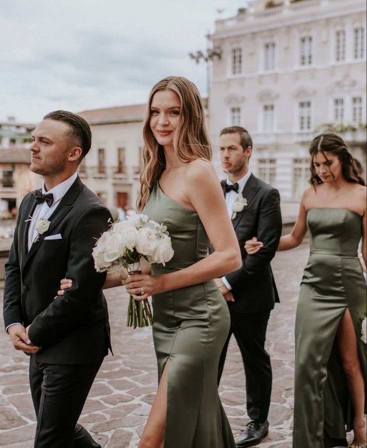 the bride and groom are walking down the street with their bridal party in the background