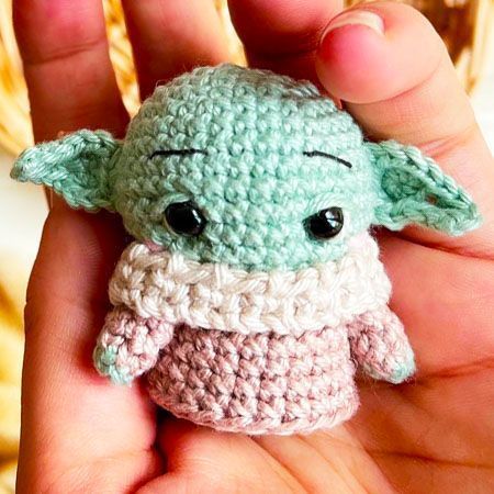 a crocheted baby yoda doll is in someone's hand