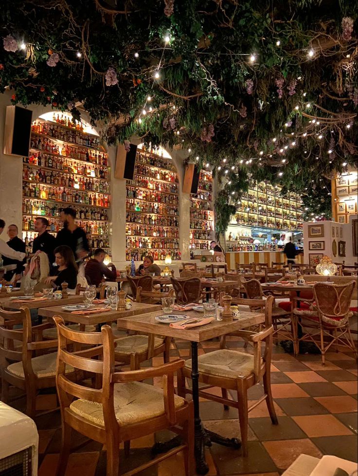 the interior of a restaurant with tables and chairs in front of bookshelves filled with books