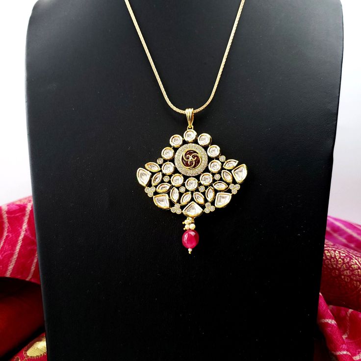 Beautiful high quality ruby kundan pendant and earrings with pave crystal accents. Just the right size - not too big, not too small. Very sparkly and eye-catching. Beautiful meenakari enamel work on reverse of pendant and earrings. This is a substantial, heavy piece. Pendant: Length 3 in. Width 2 1/2 in. Earrings: Length 1 1/2 in. Width 1 3/4 in. Weight 7 gm. Light and comfortable to wear. Shop more amazing necklaces: https://www.etsy.com/shop/boutiquebymaryam/?section_id=32674452 Be sure to vis Hand Set Kundan Pendant Earrings, Traditional Gold Plated Kundan Pendant Necklace, Traditional Gold-plated Kundan Pendant Necklace, Traditional Gold Plated Pendant Jewelry Sets, Bollywood Kundan Necklace With Pearl Pendant, Bollywood Style Kundan Necklace With Pearl Pendant, Traditional Festive Jewelry Set With Pearl Pendant, Festive Traditional Jewelry Set With Pearl Pendant, Kundan Jewelry With Pearl Pendant