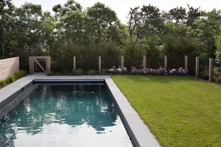 an empty pool in the middle of a garden with grass and flowers on either side