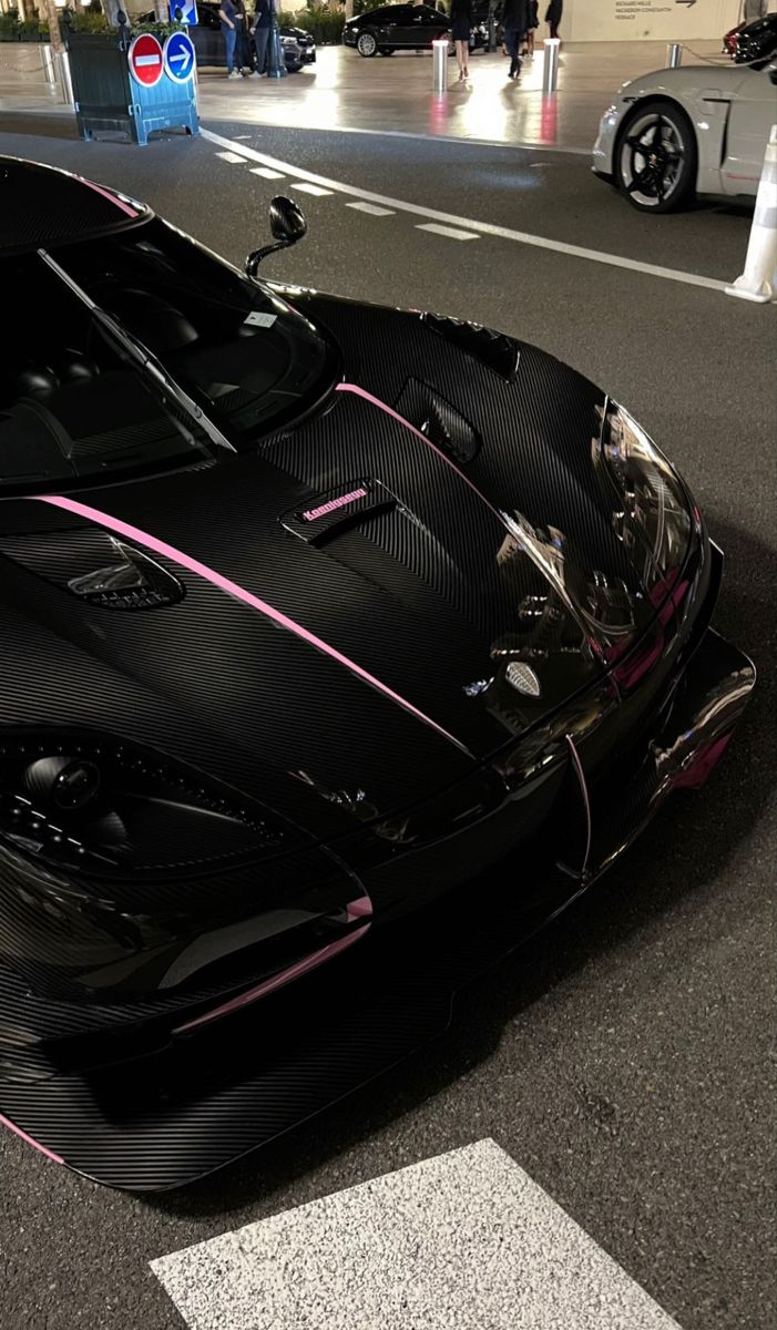 a black and pink sports car parked on the street