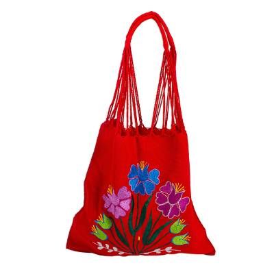 Chili red cotton hosts a bright bouquet of flowers embroidered on a colorful shoulder bag. The blossoms in Caribbean blue and purple with forest green foliage add to its festive feel. Working on the backstrap loom Petrona Perez and the Women Artisans Association craft the traditional Mexican morral a shoulder tote once used by both men and women. The warp threads are twisted then connected to become the shoulder strap. The reverse side is solid red. Red Embroidered Bag, Red Bohemian Cotton Bags, Bohemian Red Cotton Bags, Red Floral Embroidery Bag For Festivals, Red Floral Embroidery Bag For Daily Use, Red Embroidered Bag For Daily Use, Red Floral Embroidered Bag For Daily Use, Red Bags With Floral Embroidery For Festivals, Red Floral Embroidery Tote Shoulder Bag