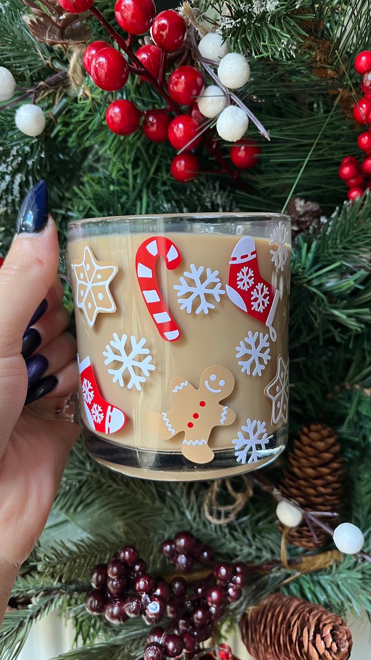 a person holding a cup with christmas decorations on it