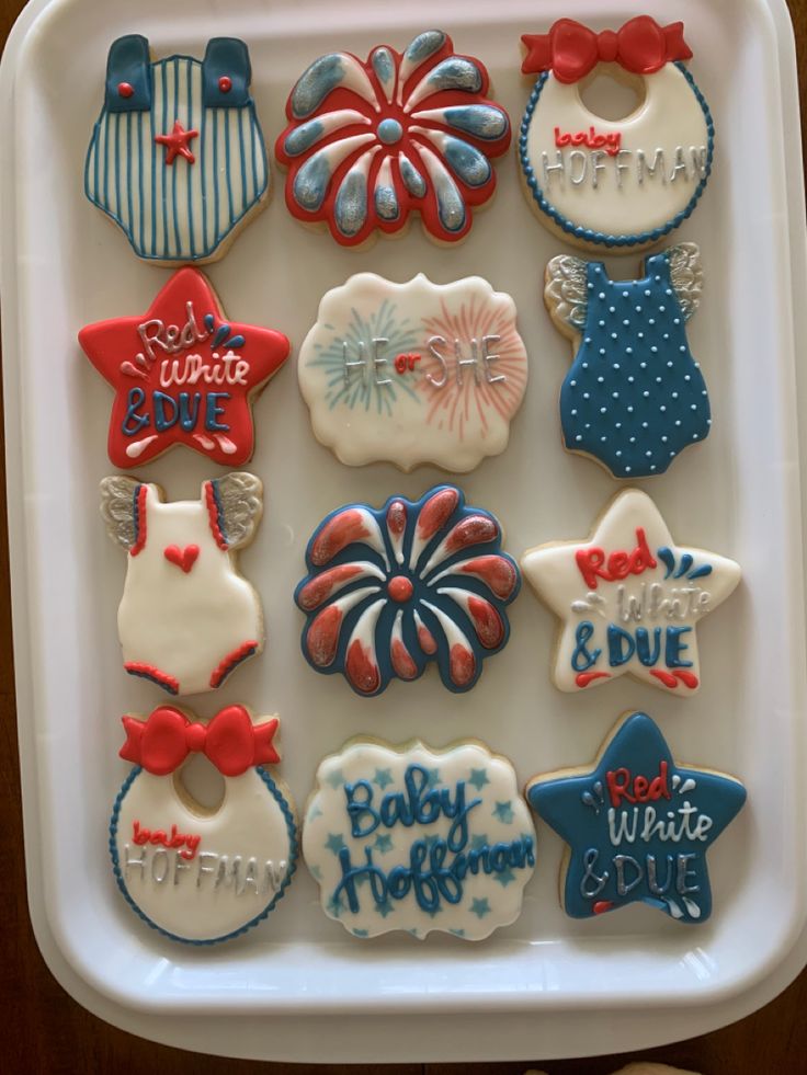 some decorated cookies in a white tray on a table and one is red, white and blue