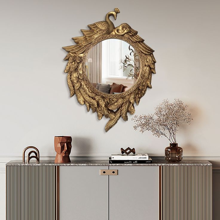 an ornate mirror hangs on the wall above a sideboard with vases and flowers