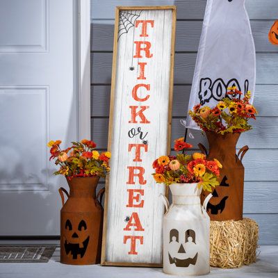 halloween decorations are displayed in front of a trick or treat sign and vases with flowers