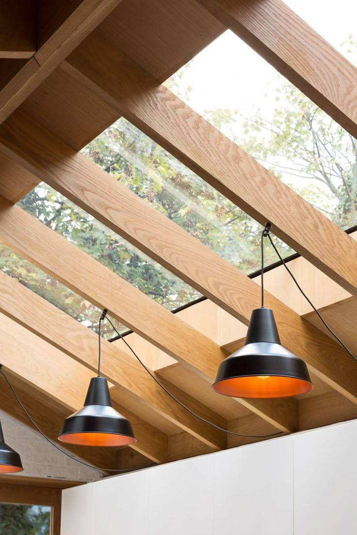 three black and orange lights hanging from the ceiling in an open room with wooden beams