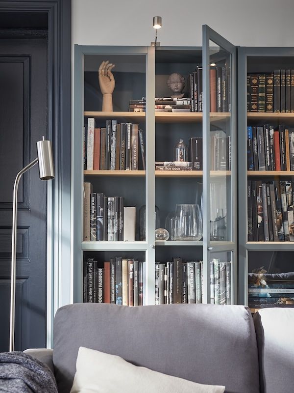 a living room filled with lots of books on top of a book shelf next to a couch