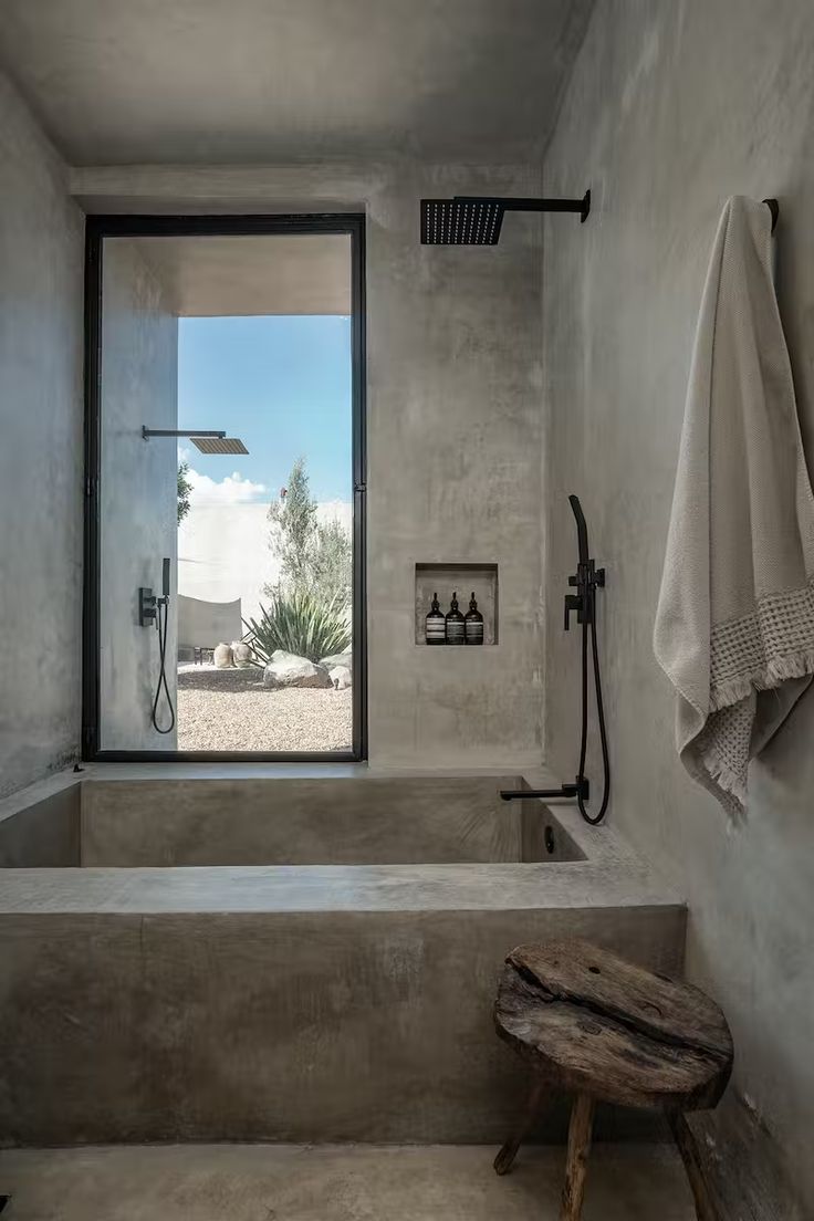 a bathroom with a large window and a bench in front of the bathtub that is built into the wall