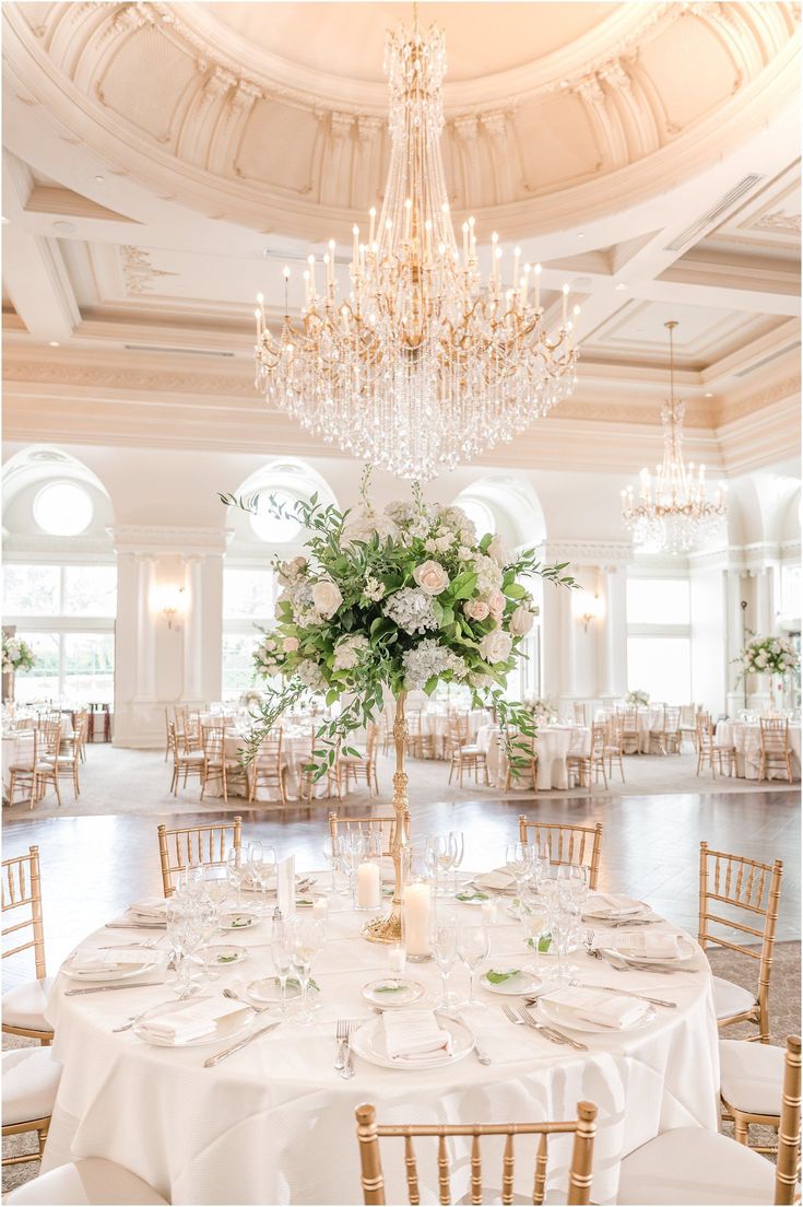 an elegant wedding reception with chandelier and white tablecloths, centerpieces and flowers