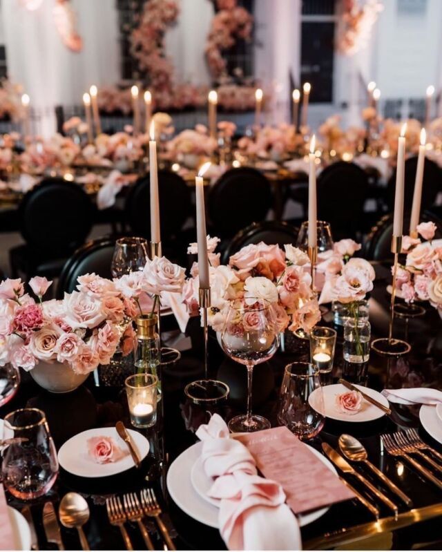 the table is set with pink flowers, candles and place settings for an elegant dinner