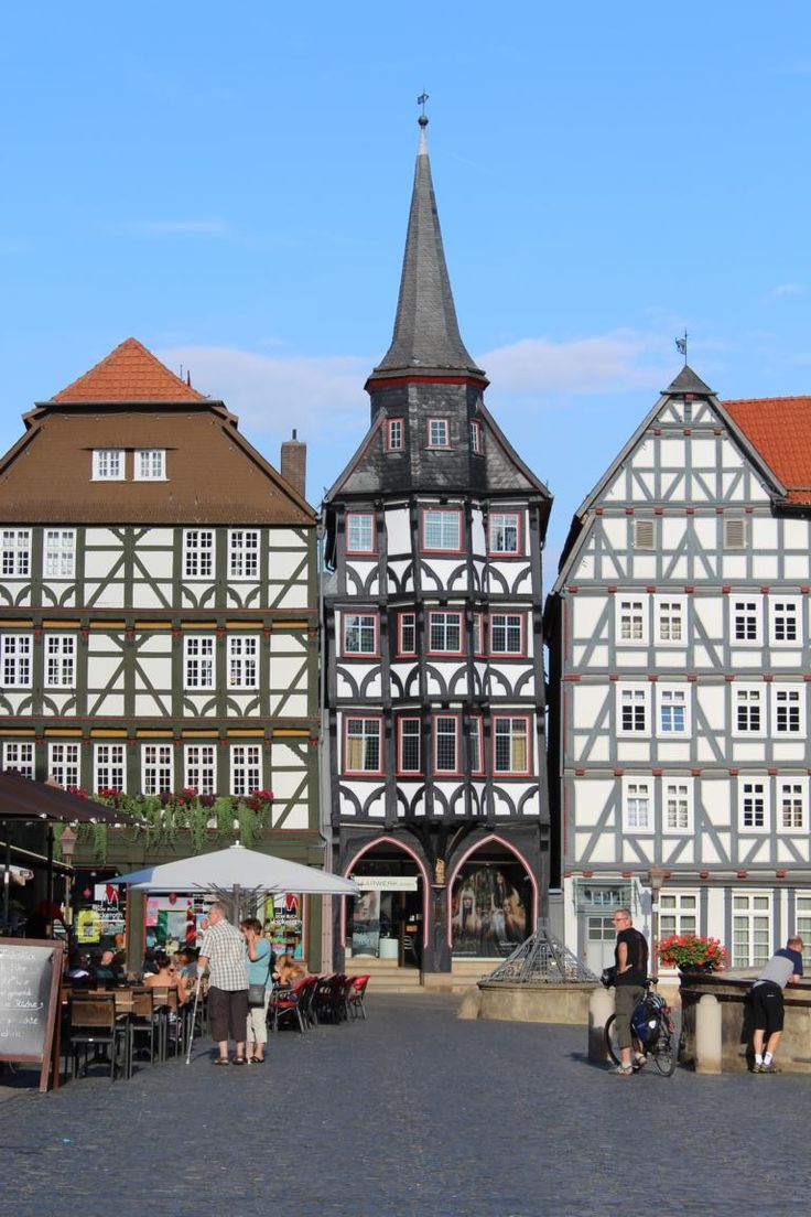 people are sitting at tables in front of old buildings on a cobblestone street