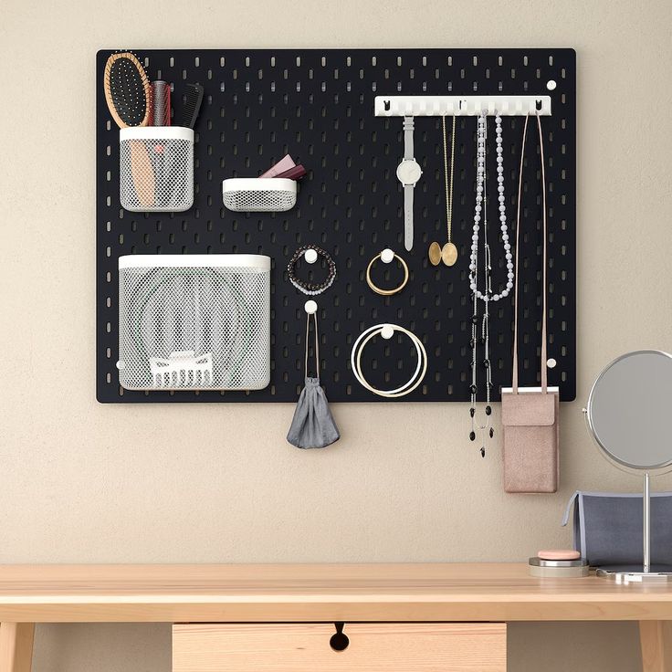 a black peg board with jewelry hanging from it's sides and a mirror on the wall