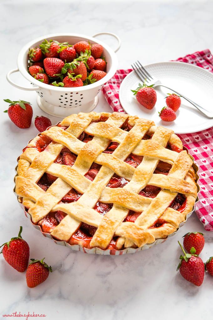 a strawberry pie sitting on top of a table next to plates and bowls of strawberries