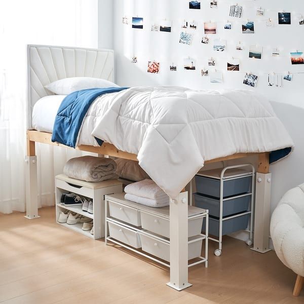 a white bed sitting next to a window with pictures on the wall and drawers underneath it