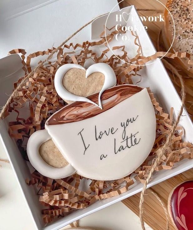 two cookies in a gift box with writing on them and hearts shaped like coffee cups