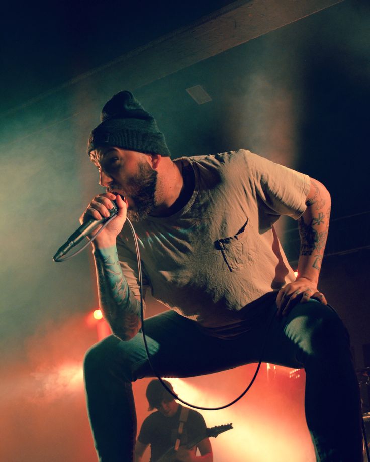 a man on stage holding a microphone up to his ear and singing into the microphone