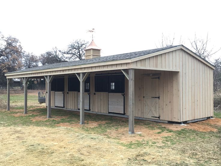 a horse barn with two stalls in the grass