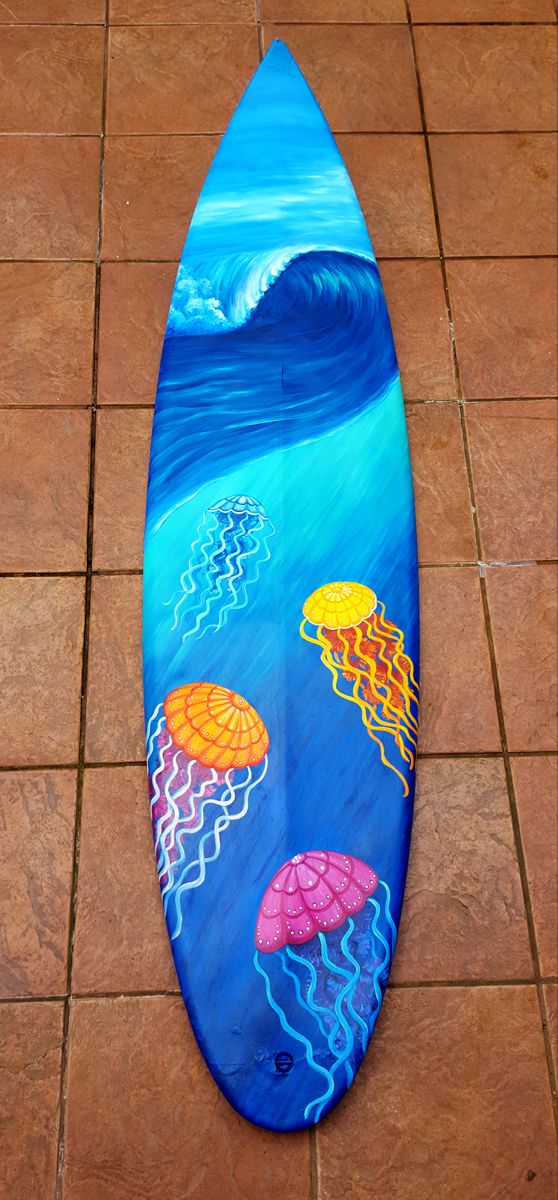 a painted surfboard with jellyfishs on it sitting on the ground next to a tile floor