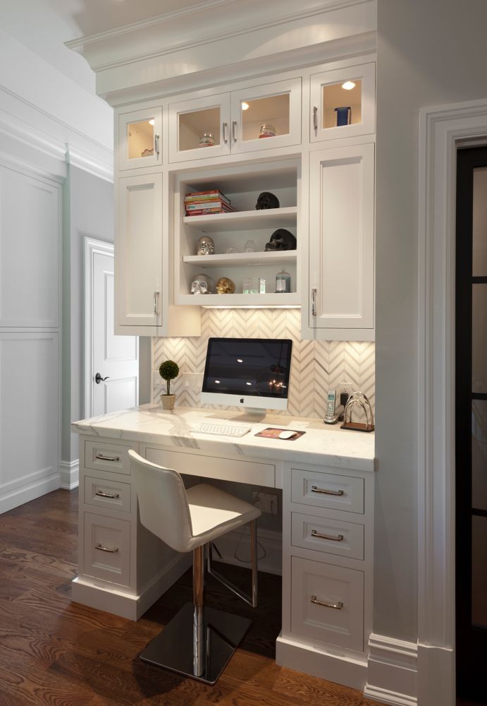 a white desk with a laptop on top of it in front of some cupboards