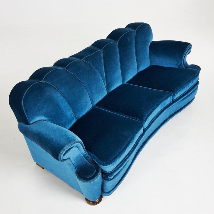 a blue velvet couch sitting on top of a white floor next to a wooden frame