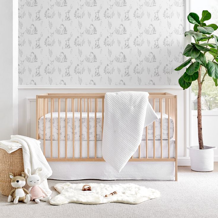 a baby's room with a crib, blanket and stuffed animals on the floor