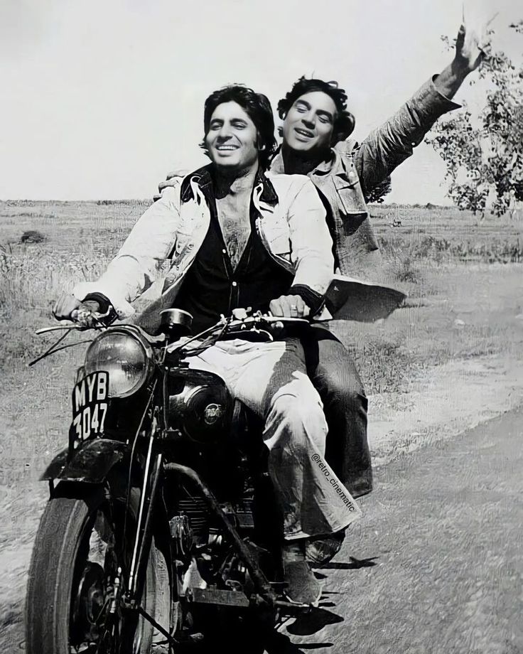 two women riding on the back of a motorcycle down a road with their arms in the air