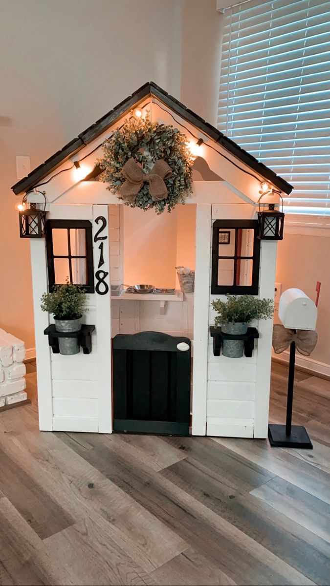 a small house made out of wood and decorated with wreaths