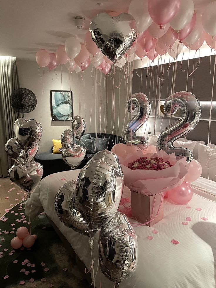 some balloons are in the shape of numbers on a bed with pink and silver confetti