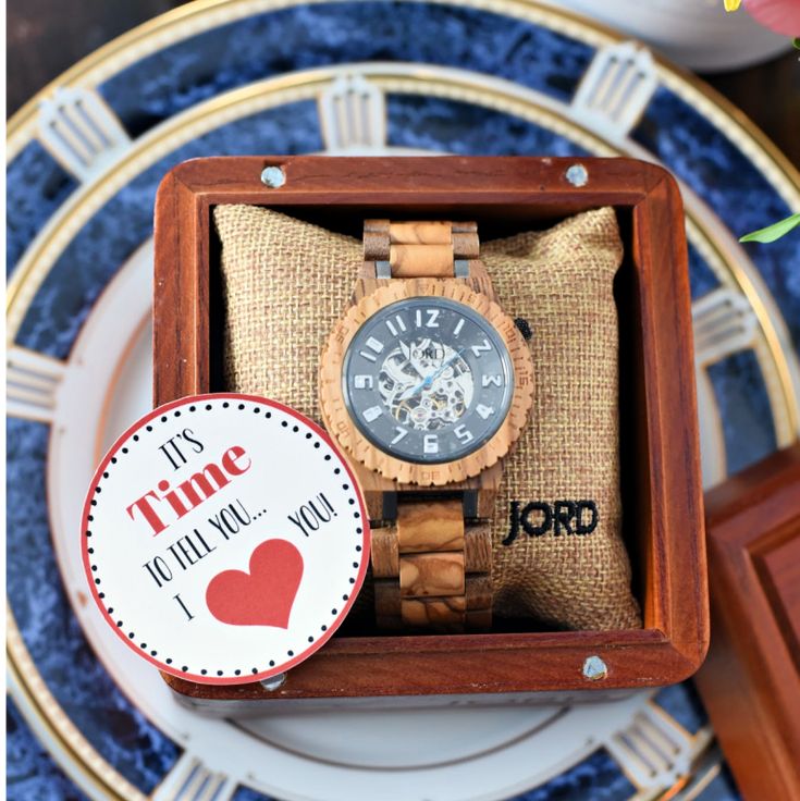 a wooden watch in a gift box on a blue and gold plated place setting