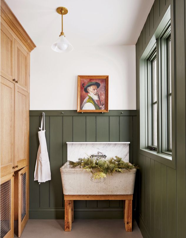 a bathroom with green paneling and a painting on the wall next to a bench