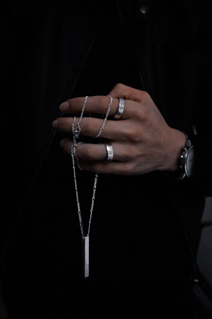 a person wearing three different rings on their fingers and one with a chain attached to it